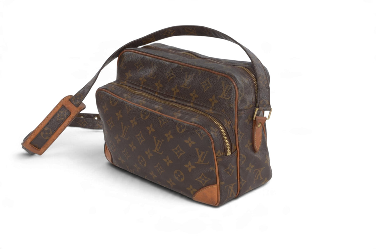 A Louis Vuitton monogram canvas shoulder bag in dark brown with tan leather trim and a matching leather luggage tag, shown on a plain white background.