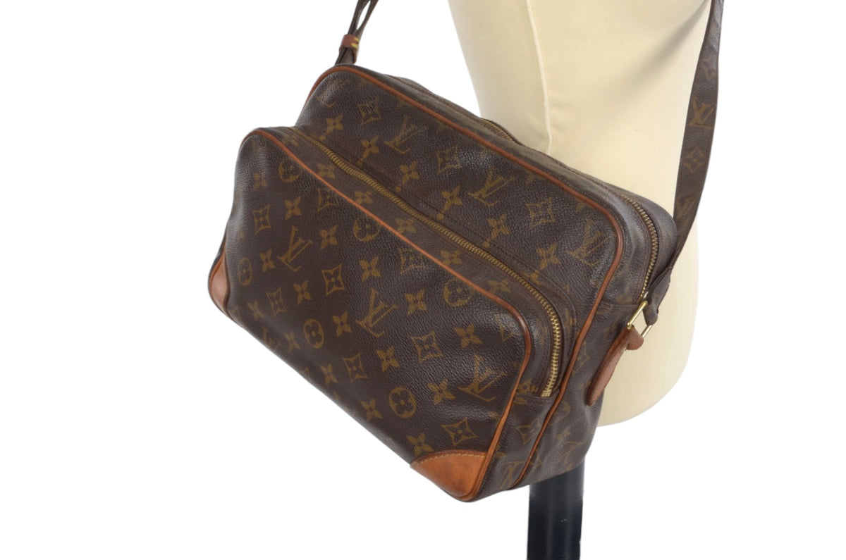 A Louis Vuitton monogram shoulder bag in brown coated canvas with tan leather trim, displayed on a cream-colored mannequin torso against a white background.